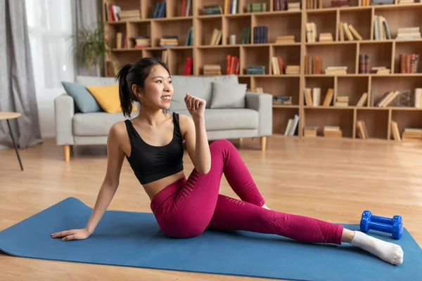 Sportowa koreańska pani robi rozgrzewkę ćwiczenia rozciągające na macie do jogi w domu, trening we wnętrzu salonu — Zdjęcie stockowe