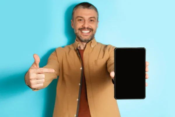 Man Showing Digital Tablet Pointing Finger At Screen, Blue Background — Stok Foto