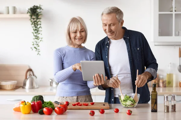 Senior couple reading food blog on digital tablet at kitchen — Stockfoto