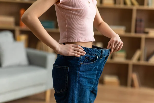 Successo perdita di peso dieta concetto. Giovane signora asiatica in grandi jeans dimostrando i risultati del suo programma di dimagrimento — Foto Stock