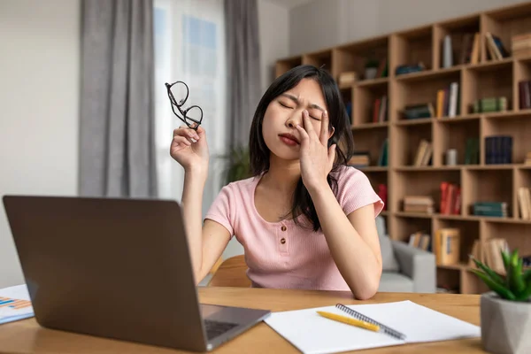 Esforço ocular. Cansado asiático senhora massagem esfregando seco irritado olhos enquanto trabalhando online no laptop em casa — Fotografia de Stock
