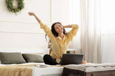 Gülümseyen Arap kadın geriliyor yatağa oturuyor.