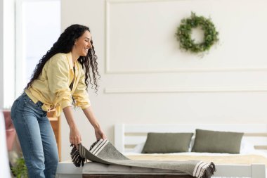 Güzel genç bayan rahat kanepeye sıcak ekose koyuyor.