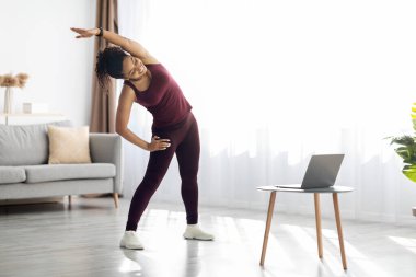 Atletik siyah bayan evde egzersiz yapıyor.