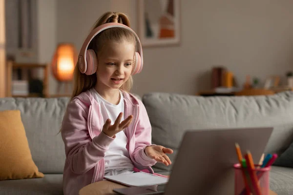 Pequena estudante fazendo chamada de vídeo via laptop aprendendo em casa — Fotografia de Stock
