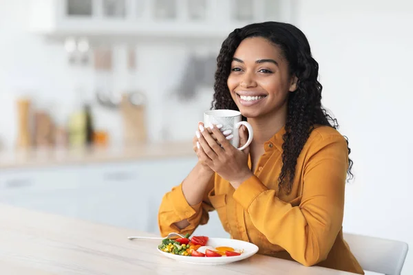 Felice donna nera godendo colazione sana e una tazza di caffè — Foto Stock
