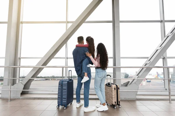 Viaggio in famiglia. Genitori con figlia in piedi vicino alla finestra in aeroporto, vista posteriore — Foto Stock