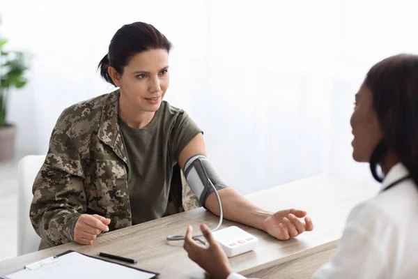 Retrato de soldado femenino que recibe chequeo de salud con la doctora negra —  Fotos de Stock