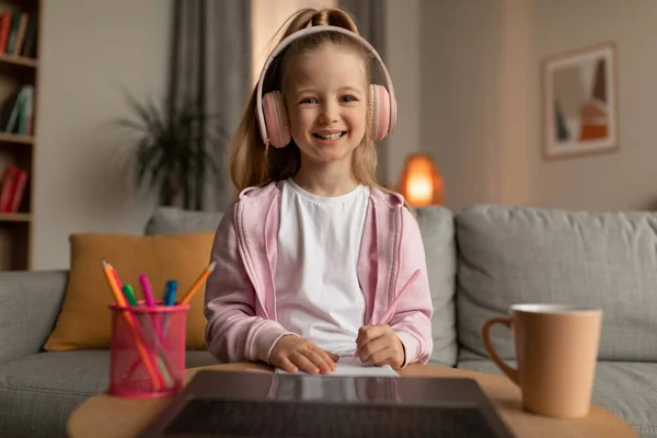 Glad liten skolflicka med hjälp av laptop lärande med anteckningar hemma — Stockfoto