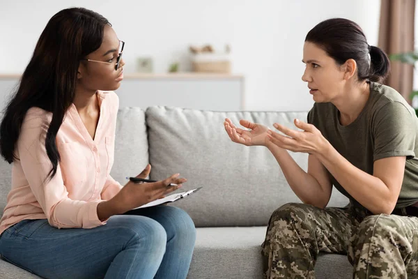 Soldado preocupado conversando com psicóloga negra durante sessão de terapia no escritório — Fotografia de Stock