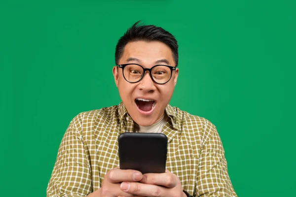 Overjoyed mature asian man in glasses looking at smartphone in shock, amazed at promo sale or huge discount — 스톡 사진