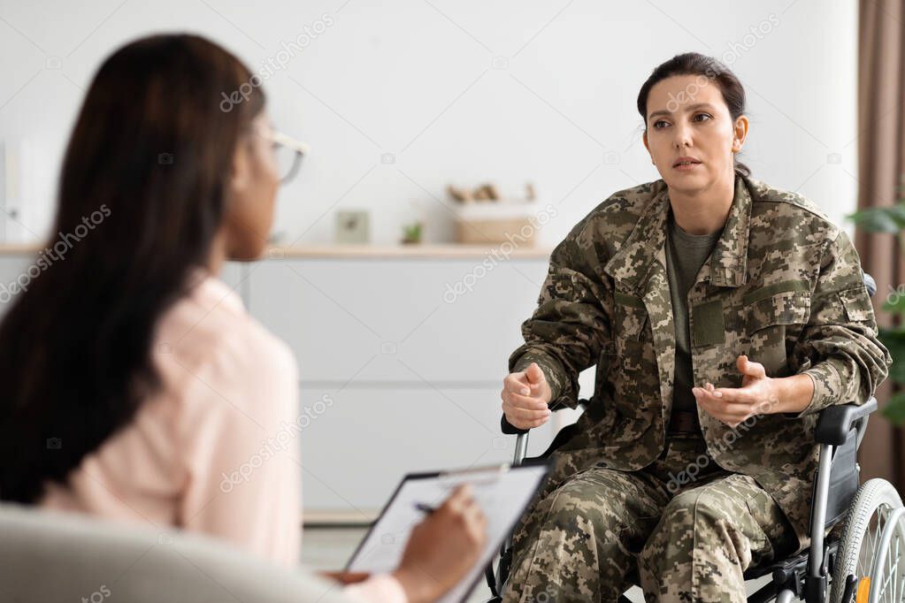 Young military woman with disability sitting in wheelchair, visiting psychiatrist at office