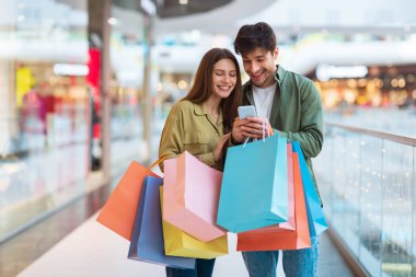 Mutlu Eşler Alışveriş Yapıyor ve Cep Telefonu Kullanıyor Alışveriş merkezinde