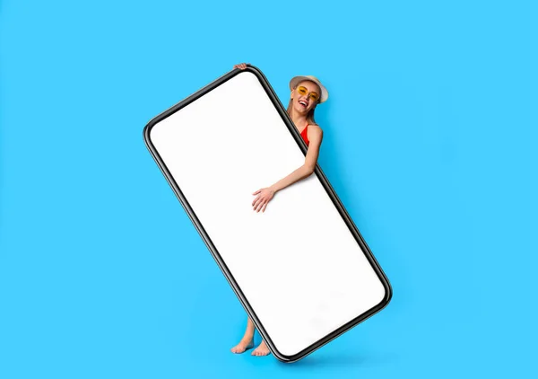 Vacation Offer. Excited young woman wearing swimsuit holding big blank smartphone — Stockfoto