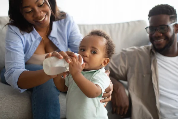 Jonge Afro-Amerikaanse ouders voeden kind uit fles — Stockfoto