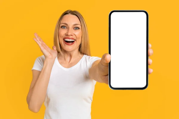 Happy surprised excited pretty millennial european blond woman in white t-shirt show smartphone with blank screen — Foto de Stock