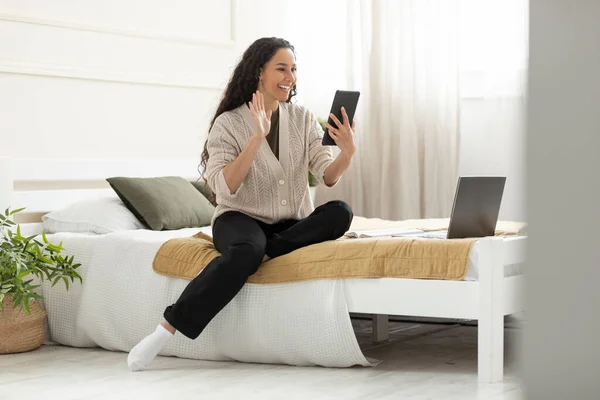 Mujer joven sonriente saludando con la mano usando tableta digital — Foto de Stock