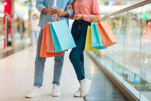 Sposi irriconoscibili che fanno shopping in piedi tenendo borse shopper nel centro commerciale — Foto Stock