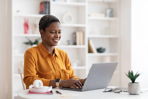 幸せなアフリカ系アメリカ人女性フリーランサー使用ノートパソコンで自宅 — ストック写真