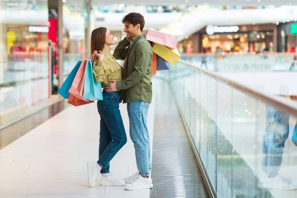 Happy Couple Of Buyers Shopping Together Standing Embracing In Mall — Stock Photo, Image