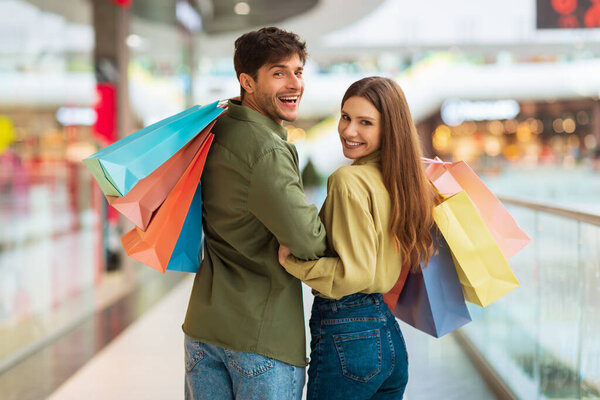 Счастливые покупатели пара покупок Позирование холдинга сумки в торговом центре