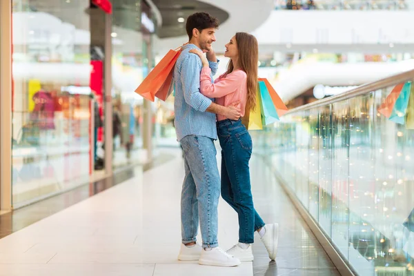 Couple On Shopping Hugging Holding Shopper Bags Standing In Hypermarket — Stock Photo, Image