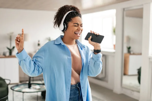 Black lady listening to music in headphones and singing — Foto Stock