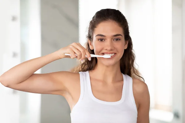 Mujer joven feliz posando con cepillo de dientes cepillando dientes en el baño — Foto de Stock