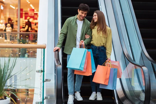 Conjoints faisant du shopping debout sur les escaliers portant des sacs dans le centre commercial — Photo