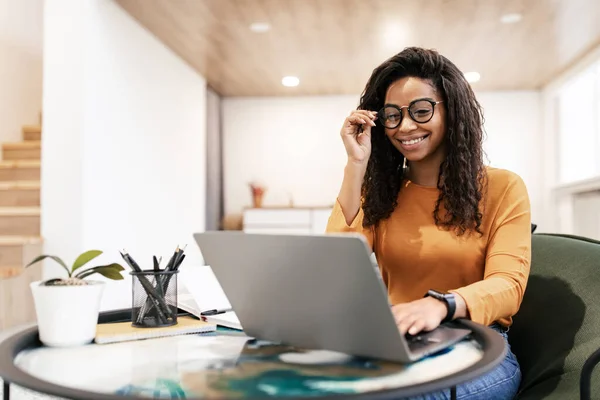 Ritratto di donna nera sorridente che usa il computer portatile a casa — Foto Stock