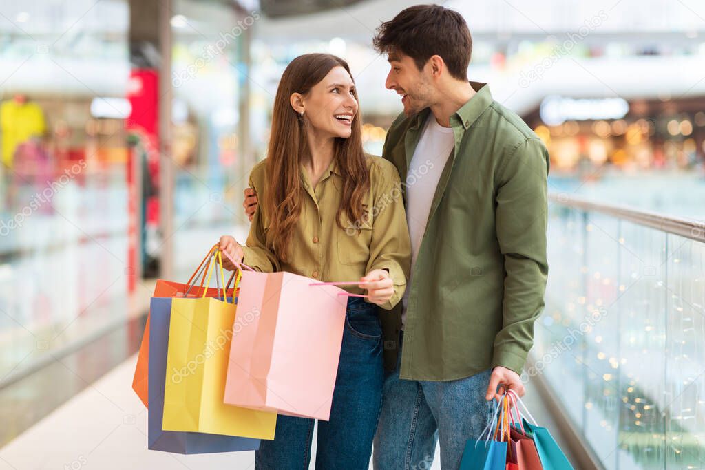Joyful Couple Doing Shopping Holding Colorful Shopper Bags In Mall