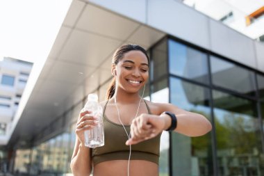 Zenci kadın akıllı bakışlar, spor aktivitelerini izlemek, müzik dinlemek, açık havada su içmek.