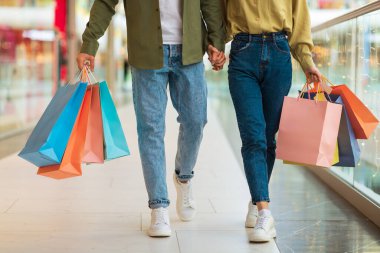 Renkli alışveriş torbaları taşıyan çift alışveriş merkezinde yürüyor.
