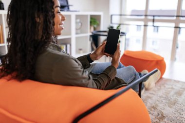 Smiling black woman using phone at home, mockup