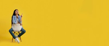 Neşeli, düşünceli, hoş, Asyalı bir kadın. Sandalyeye oturmuş, boş bir yeri işaret ediyor.