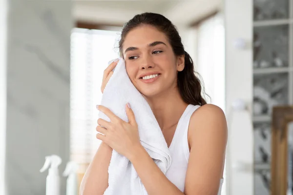現代のバスルームに立つタオルで幸せな女性の乾燥顔 — ストック写真