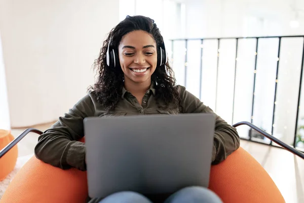 Smiling black woman in headset using pc at home — Stok fotoğraf