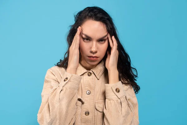 Verdrietig moe jong europees dame brunette lijdt aan hoofdpijn, drukt handen naar tempels — Stockfoto