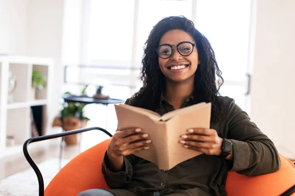 Uśmiechnięta czarna kobieta w książce do czytania okularów i pozowanie — Zdjęcie stockowe
