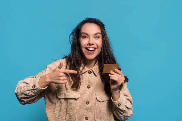 Щасливий здивований смішний молодий кавказька брюнетка дама з відкритими точками рота пальцем в кредитній картці — стокове фото