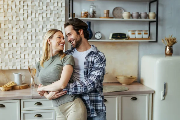 Joven europeo satisfecho abrazando a su esposa en el interior de la cocina moderna. Amor, relación y romanticismo —  Fotos de Stock