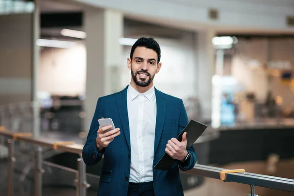 Cheerful confident millennial middle eastern man with beard in suit use tablet and smartphone in office interior — Foto de Stock