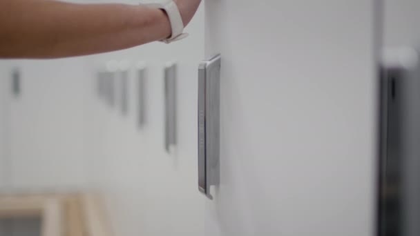 Modern safety technologies at public places. Close up of woman locking locker at gym dressing room with digital bracelet — Stockvideo