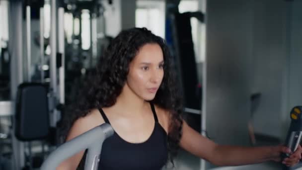 Активная тренировка. Молодая активная леди упражняется на тренажере для эллиптических упражнений, работает в современном тренажерном зале, свободное пространство — стоковое видео