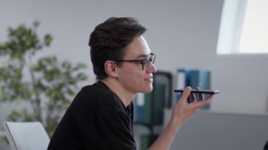 Genç pozitif adam arkadaşlarına sesli mesaj kaydediyor, akıllı telefondan mobil uygulamayla konuşuyor ve gönderiyor.,