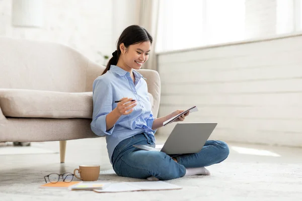 Allegro giovane donna asiatica seduta sul pavimento con laptop — Foto Stock