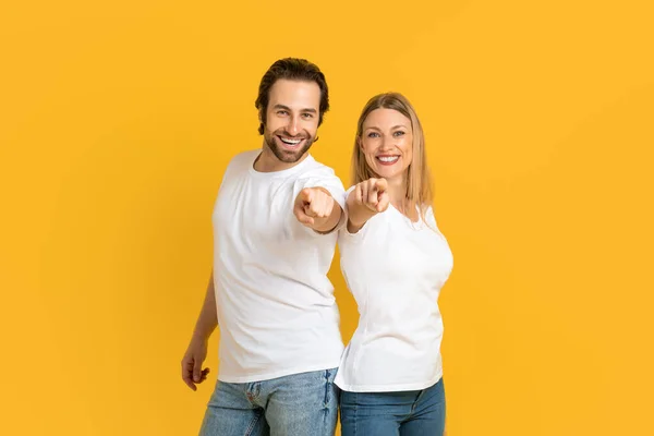 Smiling confident millennial european husband and wife in white t-shirts point fingers at camera — Photo