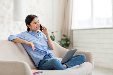 Neşeli Koreli iş kadını evden çalışıyor, telefonla konuşuyor.