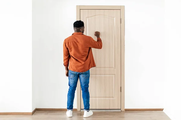 ドアをノックする黒人男性バックカメラの屋内に立つ — ストック写真