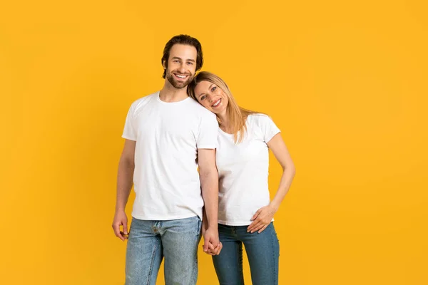 Cheerful handsome millennial caucasian man and woman in white t-shirts hold hands, enjoy moment — Foto de Stock